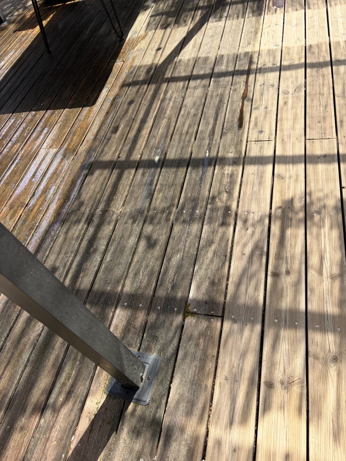 Terrasse en bois pendant 2 Planches de bois mouillées projetant des ombres sur le sol.